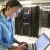 Caucasian woman technician running diagnostics on computer servers in a server farm.