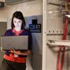 Caucasian woman technician working on computer servers in a server farm.