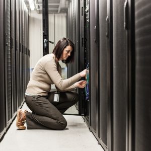 Caucasian woman technician working on computer servers in a server farm.