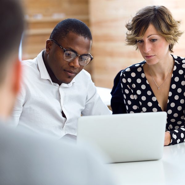 Group of intelligent young businesspeople working with laptop on