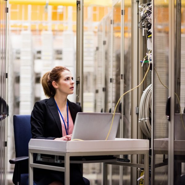 Technician using laptop while analyzing server